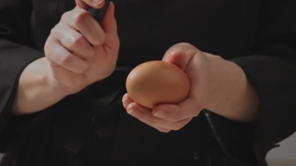 O confeiteiro quebra o ovo com uma faca e o derrama na farinha. — Vídeo de Stock