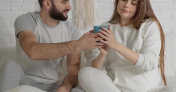 O marido entrega sua esposa uma xícara de chá e a abraça firmemente, aproveitando o momento — Vídeo de Stock