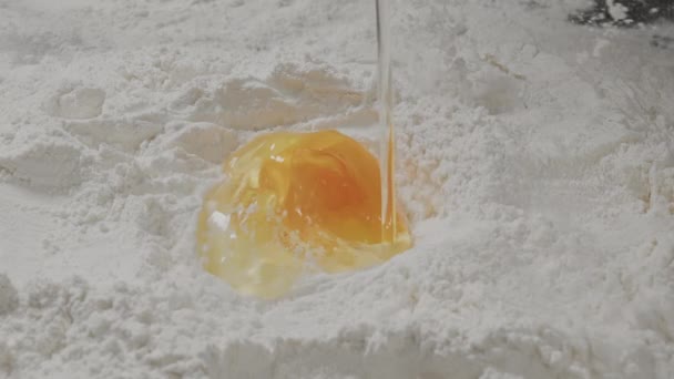O ovo partido caiu na farinha. Um ovo na farinha fecha-se. O processo de cozinhar. — Vídeo de Stock