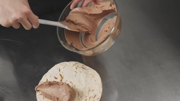 O creme de chocolate é aplicado no biscoito. Estágio de formação de bolo. — Vídeo de Stock