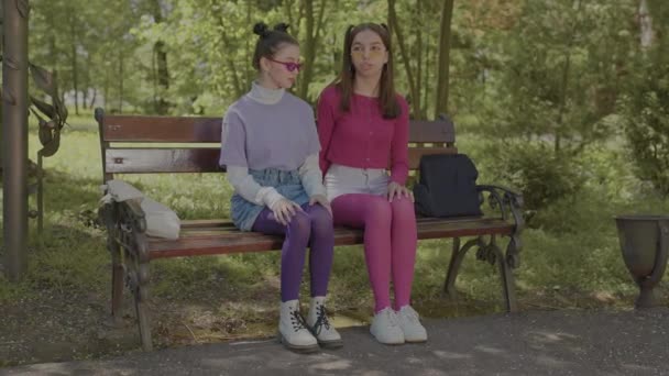 Twee meisjes zijn stiekem verliefd op elkaar. Tieners zitten in het park en praten.. — Stockvideo