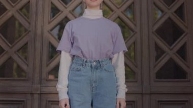 A teenager dressed in bright clothes shows a fuck and at the same time looks at the camera.