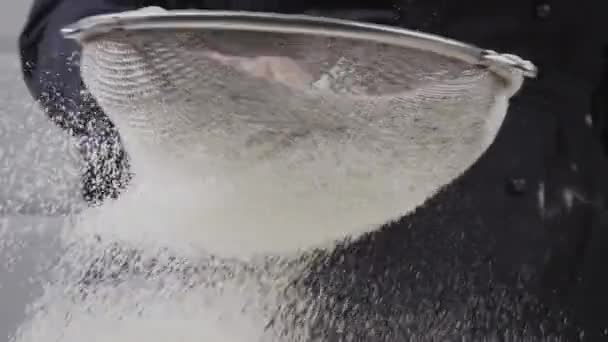 白い小麦粉は大きなふるいでふるいにかけられます。テーブルの上に落ちた小麦粉. — ストック動画