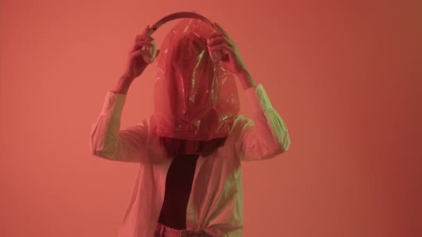 ผู้หญิงสวมถุงพลาสติกบนหัวของเธอและฟังข่าวในหูฟังเกี่ยวกับพลาสติกในโลก . — วีดีโอสต็อก
