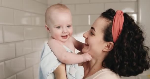 Mam speelt met baby 's in de badkamer. Baby in een handdoek na het baden. — Stockvideo