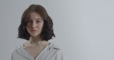The girl closes her mouth with her hands. Girl on a white background.