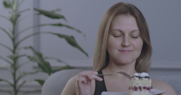 Eine Frau isst appetitlich ein Stück Kuchen mit einer Gabel und hält es in ihren Händen. — Stockvideo