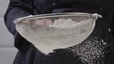 Video close up of sifting flour. Organic flour is sifted through a sieve.