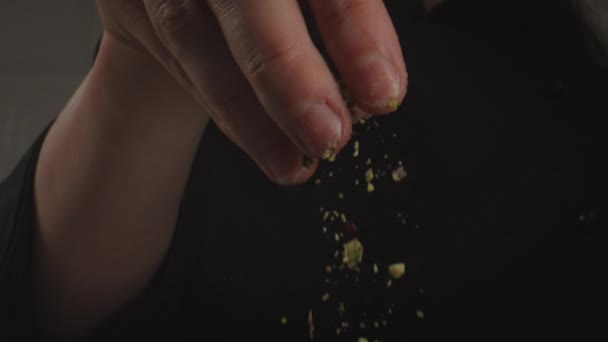 Confectioners hand close up of which is sprinkled with nut crumbs. — Stok video