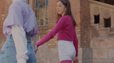Two girls walk around the city holding hands. Mini travel girls girlfriends on summer vacation.