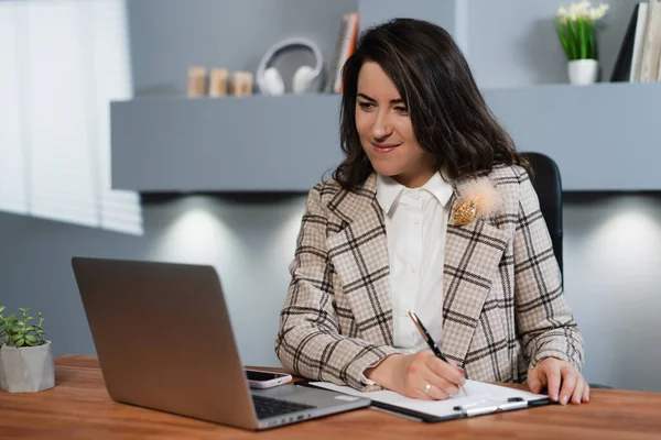 The girl works in the office at the computer. Office woman working with customers online.