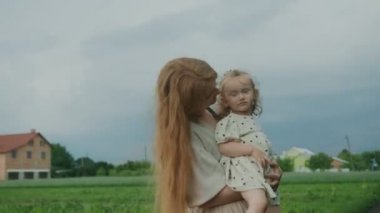 Anne, bebeği ormanda kollarında sallıyor. İlkbaharda ormanda bir yürüyüş.