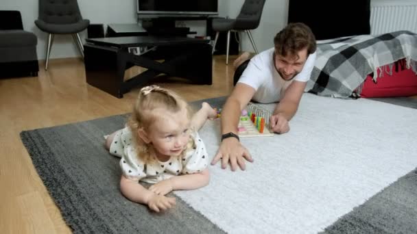 Roliga spel av föräldrar med ett barn. Föräldrar leker med barnet hemma på mattan. — Stockvideo