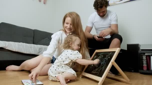 ครอบครัวเล็ก ๆ ใช้เวลาอยู่ด้วยกันในห้องนั่งเล่นในวันเกิดลูกสาวของพวกเขา — วีดีโอสต็อก