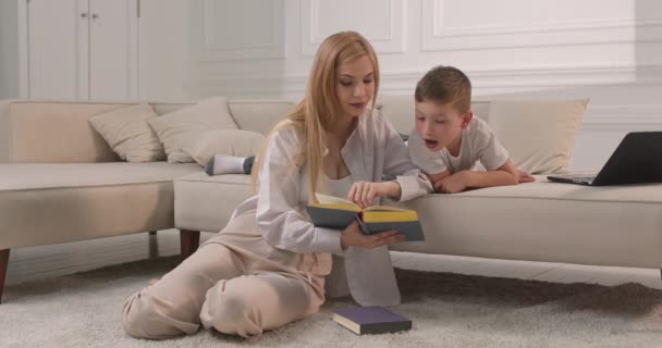 Mamma och son läser en bok i vardagsrummet. — Stockvideo