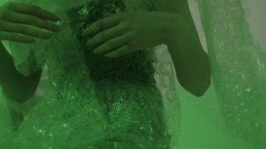 Kız polietilen giyip el sallıyor. Plastiği tekrar kullanmaları için herkesi teşvik et.