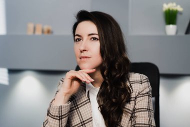 Kız bir sandalyede oturuyor ve başka tarafa bakıyor. Yüze yakın el, yana bak..