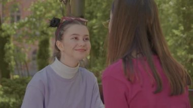 İki kız birbirlerinin gözlerine bakıp konuşuyorlar. Kızlar dışarıda vakit geçirir..