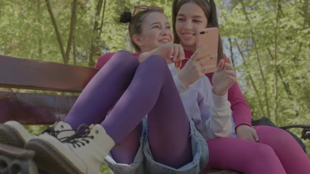 Två tjejer gör en souvenirbild i sommarparken. Glada tjejer som umgås. — Stockvideo
