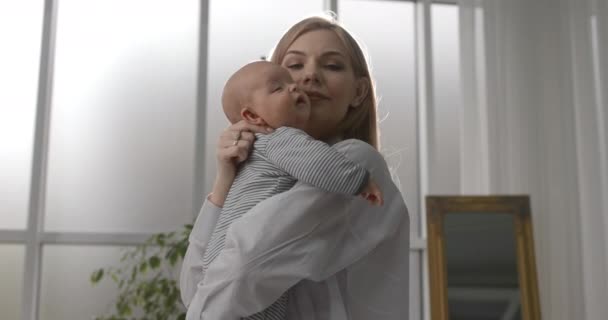 Mom hugs the baby and holds a yogi in her arms. Beautiful woman with a newborn baby. — Stock Video