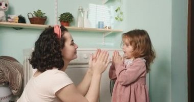 Anne ve kızı avuç içleriyle oynuyorlar. Kızı banyoda annesine sarılıp öpüyor..