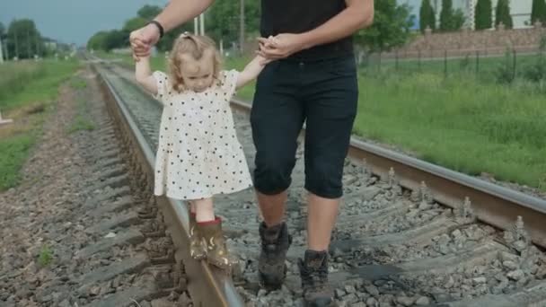 Papa hält seine Töchter an den Händen und sie laufen auf der Eisenbahn. — Stockvideo