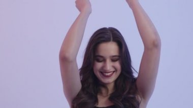 Kız dans ediyor ve kameraya gülümsüyor. Güzel kız elleriyle dans ediyor..