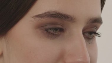 Genç bir kız beyaz arka planda çok ağlar. Güzel bir kız mutsuz olduğu için ağlar. Yüzünü kapat..