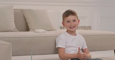 Çocuk sınıfa parmaklarıyla gösterir. Çocuk yere oturur ve sınıfa gösterir..