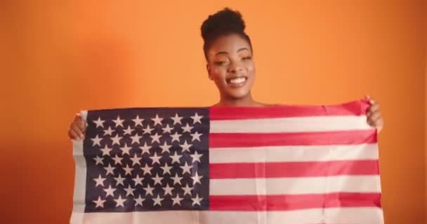 A menina segura na frente da bandeira da América e se alegra. Vídeo com a bandeira de uma menina bonita. — Vídeo de Stock