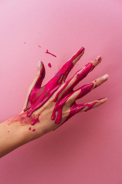 Hand in pink paint on a pink background. Gentle manicure. Female hand.