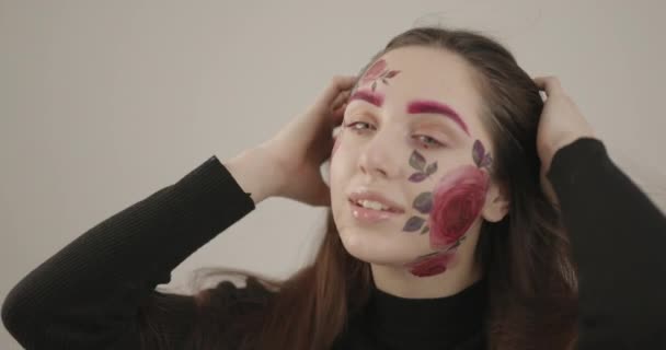 Krásná modelka pózující pro kameru ve studiu, hrající si s vlasy a krásně natřenou tváří — Stock video