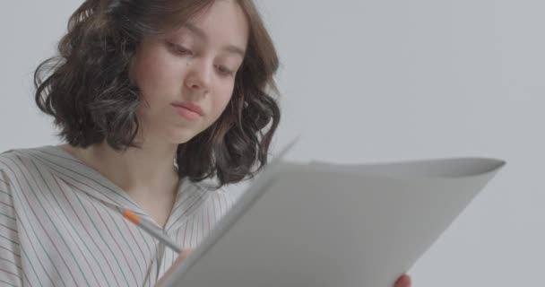 Tvář dívky, která se soustředí na kreslení. Dívka s papírem v ruce a tužkou. — Stock video