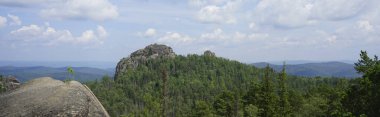 Uçurumun tepesinden Sibirya Taygası 'na bak. Kayalar ve bulutlu mavi gökyüzü. Dağ manzarası. Krasnoyarsk 'taki Stolby Ulusal Parkı. Kaya.
