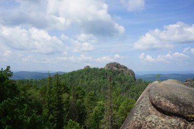 Uçurumun tepesinden Sibirya Taygası 'na bak. Kayalar ve bulutlu mavi gökyüzü. Dağ manzarası. Krasnoyarsk 'taki Stolby Ulusal Parkı. Kaya.