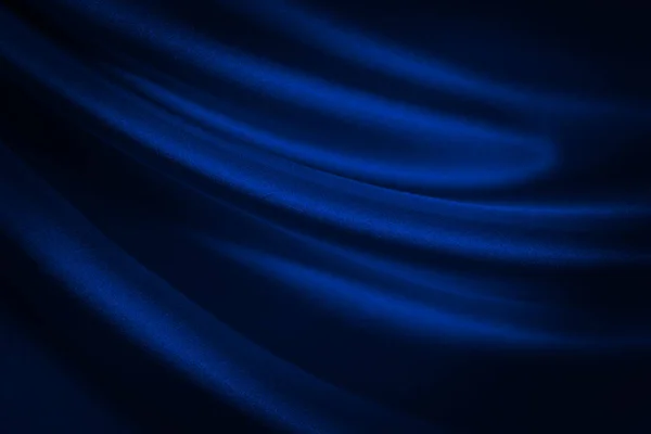 Black blue abstract background. Dark blue silk satin texture background. Shiny fabric with wavy soft pleats. Dark blue elegant background with copy space for your design. Liquid wave effect.