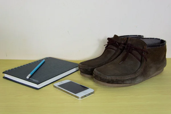 Still life with boots , book and phone on wooden table over grun — Stock Photo, Image