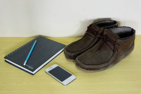 Still life with boots , book and phone on wooden table over grun — Stock Photo, Image