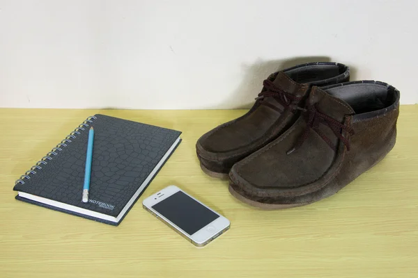 Still life with boots , book and phone on wooden table over grun — Stock Photo, Image