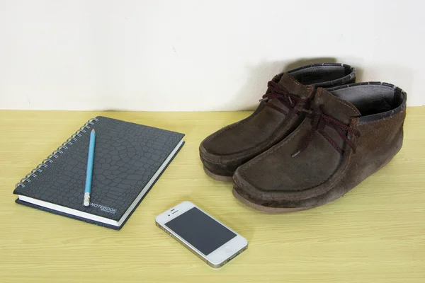 Still life with boots , book and phone on wooden table over grun — Stock Photo, Image