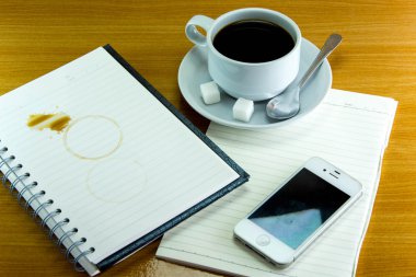 Natürmort fincan kahve tabağı ile defter ve smartphone üzerinde 