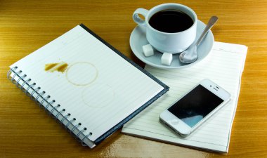 Natürmort fincan kahve tabağı ile defter ve smartphone üzerinde 