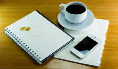 Natürmort fincan kahve tabağı ile defter ve smartphone üzerinde 