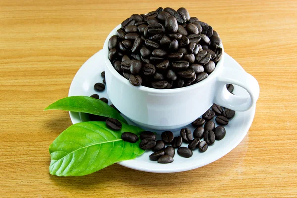 Bodegón Copa de granos de café y deja café en la mesa de madera — Foto de Stock
