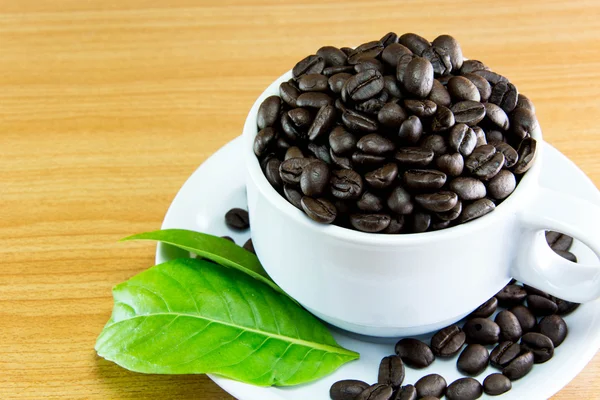 Natürmort fincan kahve çekirdekleri ve yaprakları kahve ahşap tablo — Stok fotoğraf