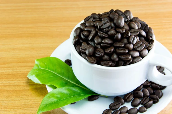 Still life Cup of coffee beans and leaves coffee on wooden table — Stock Photo, Image