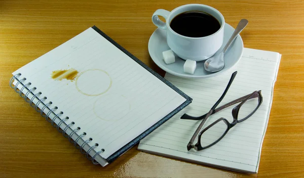 Stillleben Tasse Kaffee auf Untertasse mit Notizbuch und Gläser auf — Stockfoto