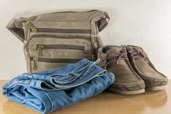 Casual adam, çizme ve ahşap masa g üzerinde çanta ile natürmort