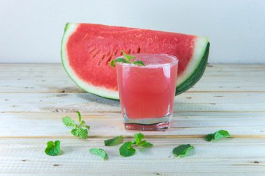 Ahşap masa üzerinde bardak taze karpuz suyu ile nane yaprakları