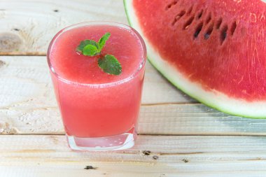 Ahşap masa üzerinde bardak taze karpuz suyu ile nane yaprakları